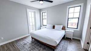 Een slaapkamer met een bed, nachtkastjes, een plafondventilator en een raam.