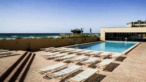 Un espace piscine avec des chaises longues et vue sur l’océan.