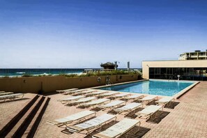 Un área de piscina con sillones de descanso y vistas al océano.