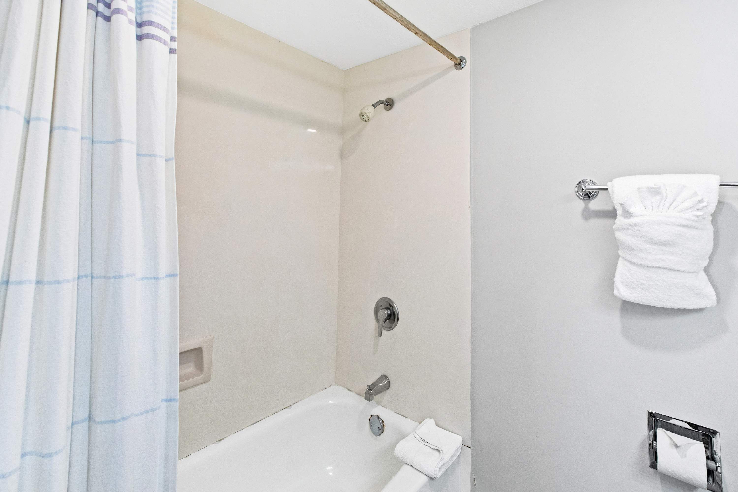 Ein Badezimmer mit Dusche, Badewanne, Handtuchhalter und Toilettenpapierhalter.