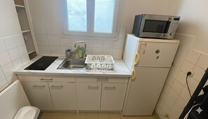 Eine kleine Küche mit Spüle, Mikrowelle und Kühlschrank.