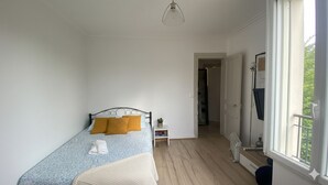 A bedroom with a bed, a bedside table, a lamp, and a window. - Lovely Apartment in Montmartre Paris - Fast Wifi (Paris)