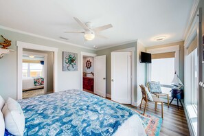 Une chambre à coucher avec un lit, un ventilateur de plafond, une télévision et une vue sur l’extérieur.