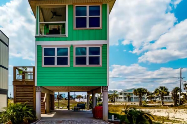Une maison à deux étages, avec une façade verte et un porche abrité.