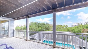 Una terraza techada con piscina, barandas blancas y vistas a una zona residencial.