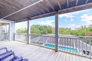A covered deck with a pool, white railings, and a view of a residential area. - Dog-friendly home near the beach with private pool & gym (St. George Island)