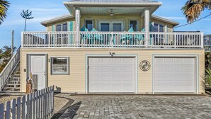 A two-story house with a balcony, a garage, and a small porch area. - Updated beach house with unobstructed gulf views, large deck & outdoor shower (Port St. Joe)