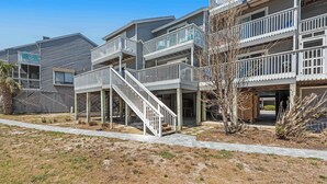 A multi-story residential building with a central staircase, balconies, and a covered outdoor area. - Dog-friendly townhome in private community with pool - near beach (Cape San Blas)