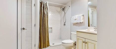 A bathroom with a shower, toilet, and sink.