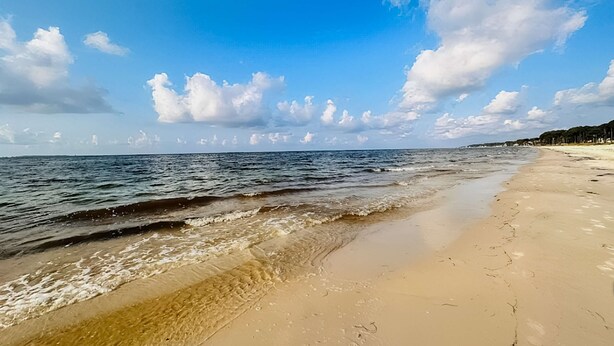 Een strand met heldere lucht en rustige golven.