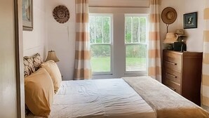 Een slaapkamer met een bed, een kaptafel, een lamp en een deur naar een balkon.