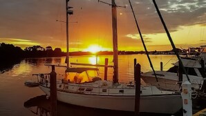 Een boot aangemeerd in een jachthaven, met een zonsondergang op de achtergrond.