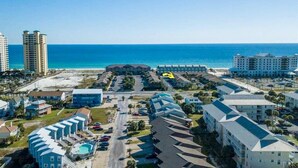 A coastal hotel with multiple buildings, a parking area, and a view of the ocean. - Pool-side condo with pool, private washer&dryer, walk to beach & free WiFi (Navarre Beach)