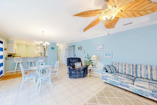 A living room with a sofa, chairs, a dining table, and a ceiling fan. - Pool-side condo with pool, private washer&dryer, walk to beach & free WiFi (Navarre Beach)