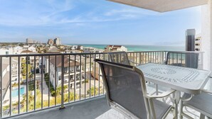 Ein Balkon mit Tisch und Stühlen, der auf eine Stadtansicht und das Meer blickt.