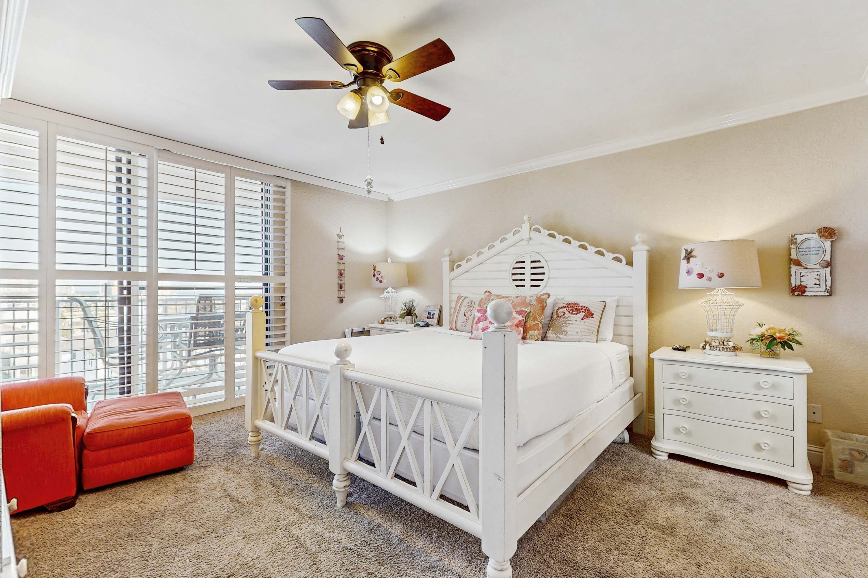 A bedroom with a white bed, a ceiling fan, a nightstand, and a window with blinds.