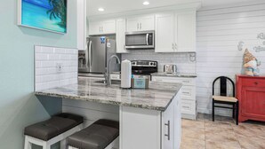 A kitchen with white cabinets, a granite countertop, a stainless steel refrigerator, a microwave, and a toaster. - Sunny condo with lake views, outdoor pool, fast WiFi, tennis & central AC (Miramar Beach)