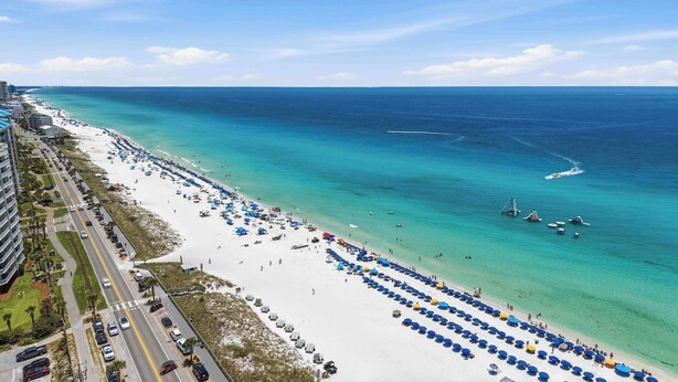 A beach with rows of umbrellas and a road alongside. - Sunny condo with lake views, outdoor pool, fast WiFi, tennis & central AC (Miramar Beach)
