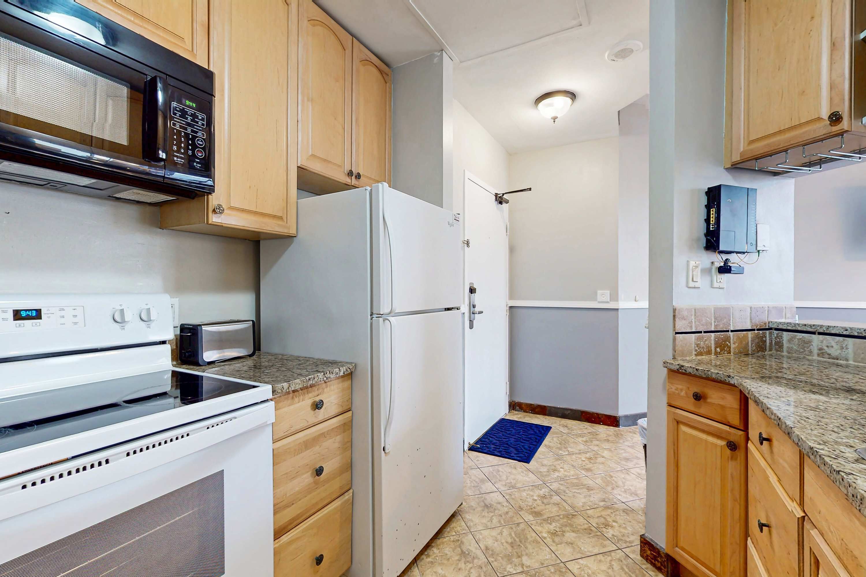 A kitchen with a microwave, oven, refrigerator, and wooden cabinets.