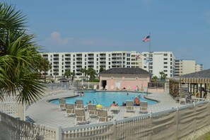 Ein Poolbereich mit Liegestühlen, ein Gebäude mit mehreren Balkonen und eine amerikanische Flagge.