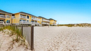 A beachfront hotel with multiple yellow buildings, balconies, and a sandy beach. - Spacious Condo, Private Wi-Fi, Bike to beach, Near shops and dining (Destin)