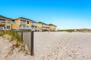 A beachfront hotel with multiple yellow buildings, balconies, and a sandy beach. - Spacious Condo, Private Wi-Fi, Bike to beach, Near shops and dining (Destin)