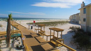 A wooden boardwalk leading to beach houses with a clear view of the ocean. - Spacious Condo, Private Wi-Fi, Bike to beach, Near shops and dining (Destin)