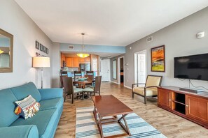 A living room with a sofa, a coffee table, a TV, and a dining area with chairs and a table. - Comfortable, Open unit, Stunning Views, Minutes to Entertainment (Destin)