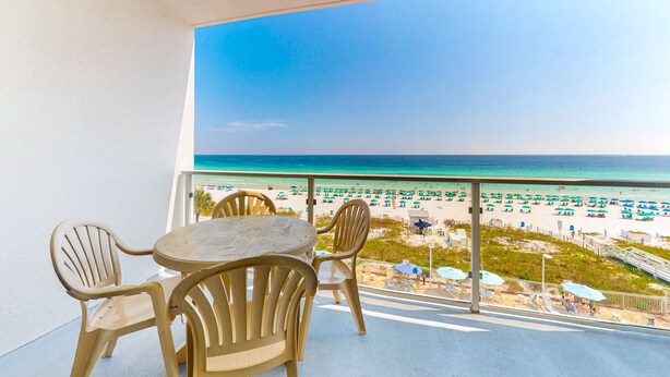 A balcony with a view of a beach, a round table, and four chairs. - Cozy condo with Gulf-front balcony & great views - near shops & dining (Destin)