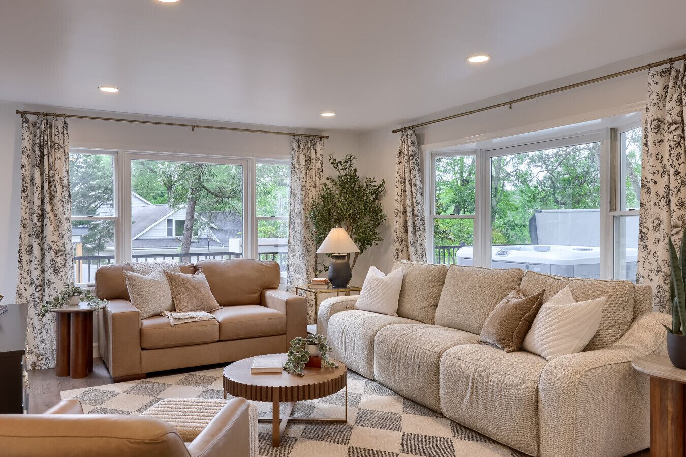 A spacious living room with two sofas, a coffee table, and large windows offering a view of the outdoors.