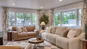 A spacious living room with two sofas, a coffee table, and large windows offering a view of the outdoors. - Welcome to the secluded waterfront oasis (Millington)