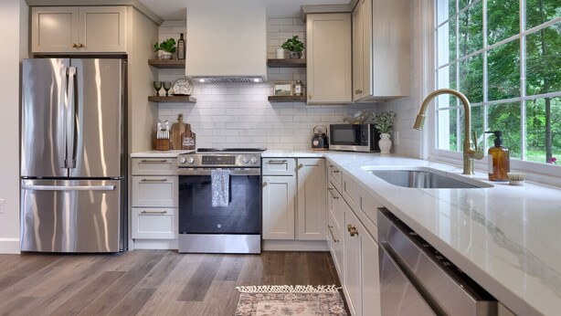 A modern kitchen with stainless steel appliances, white cabinetry, and a large window providing a view of greenery. - Welcome to the secluded waterfront oasis (Millington)