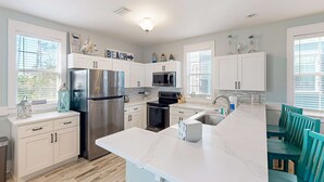 Una cocina moderna con armarios blancos, electrodomésticos de acero inoxidable y una isla central con asientos.