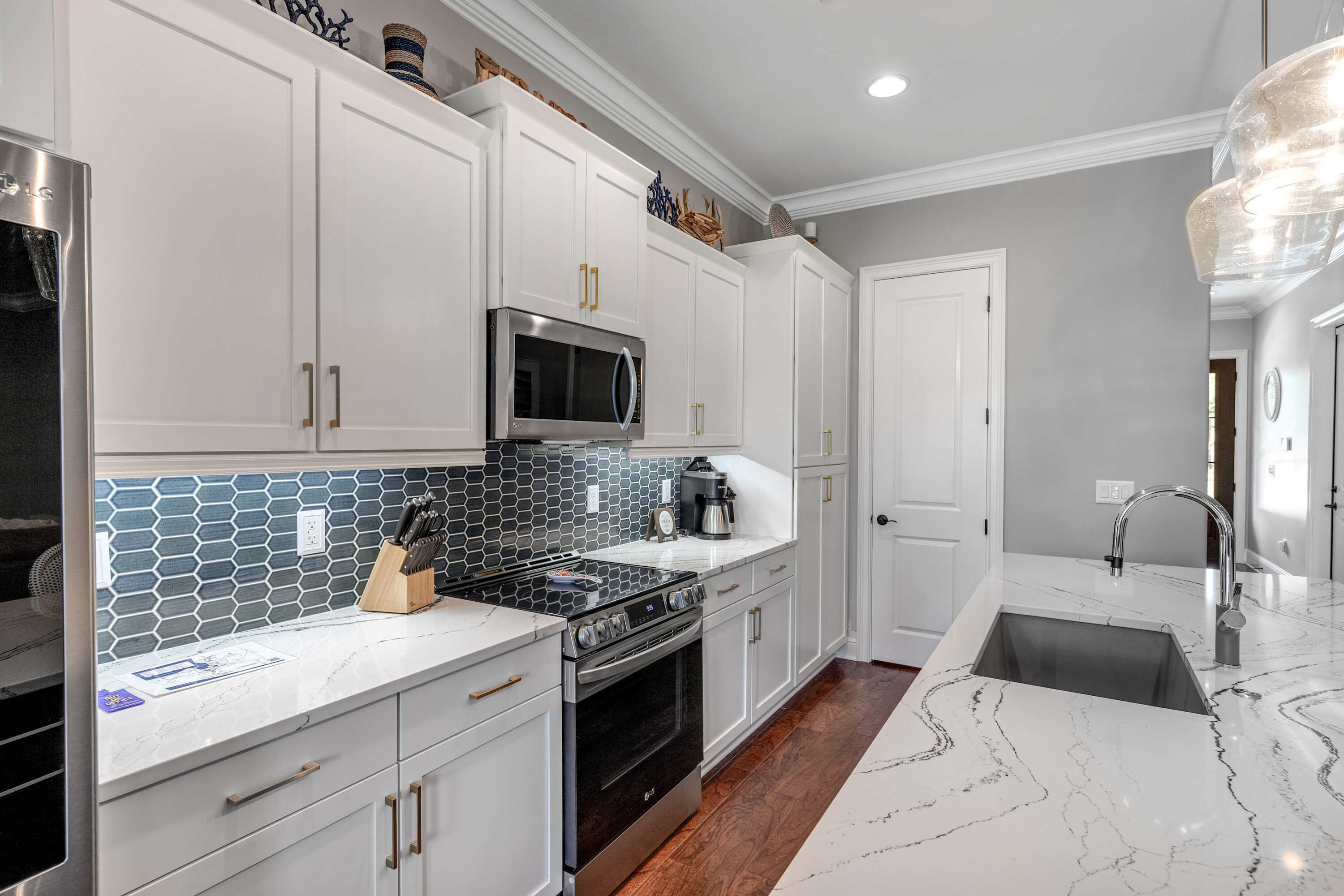 A modern kitchen with white cabinetry, a stainless steel refrigerator, a microwave, and a gas stove.