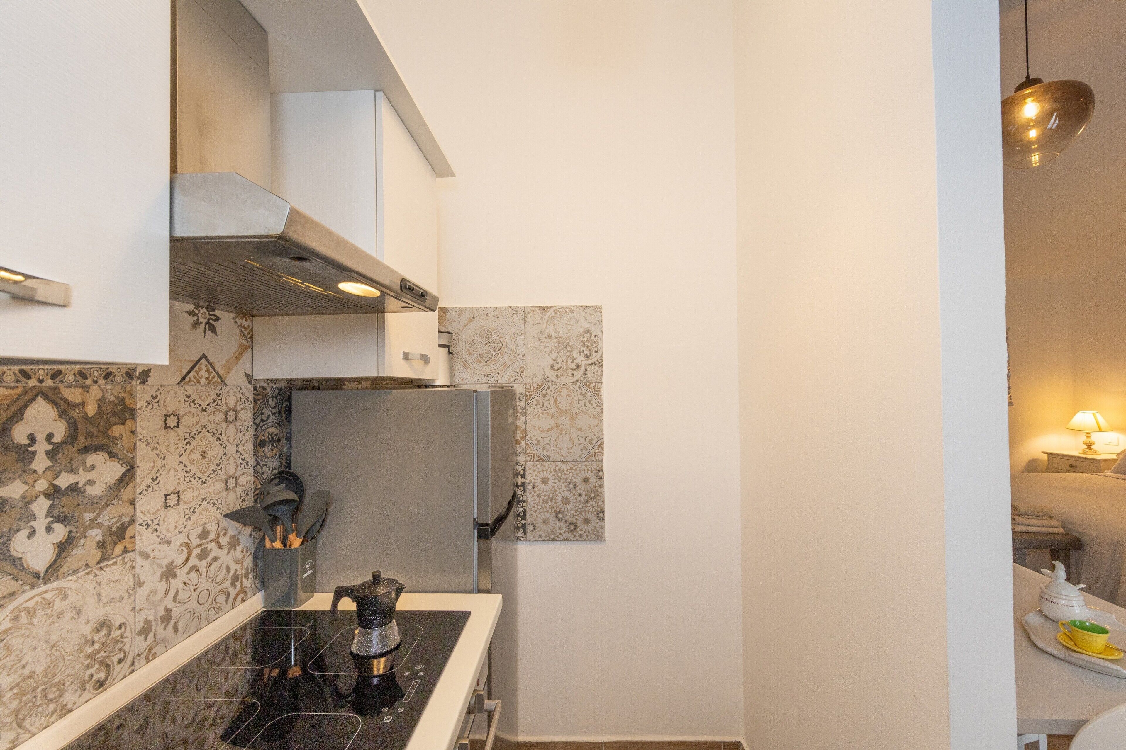 A compact kitchen with a stove, refrigerator, and patterned backsplash.