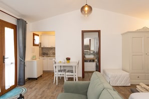 A compact living space with a kitchenette, a dining area, a sofa, and a wardrobe.