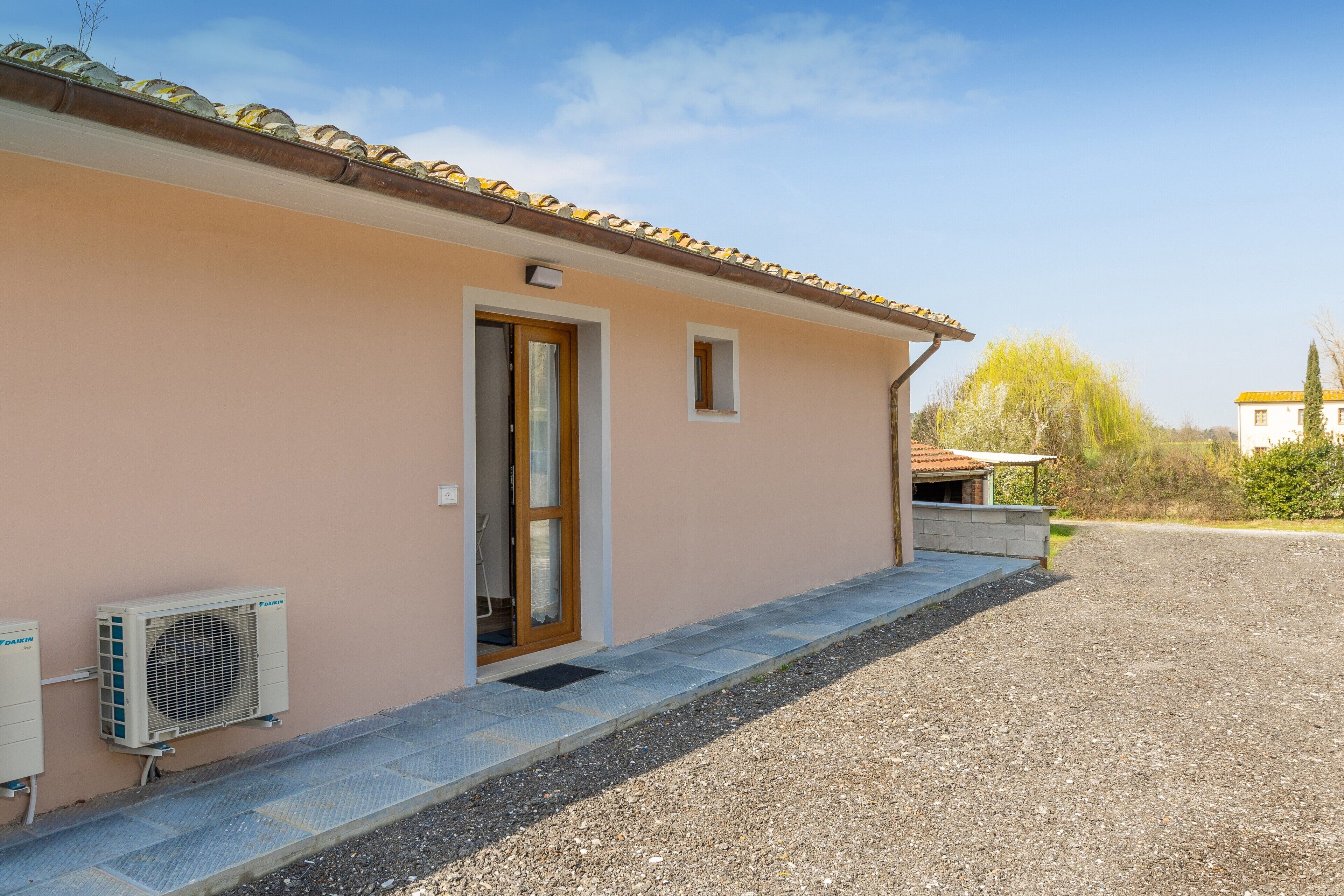 A building with a beige exterior, a wooden door, and an air conditioning unit on the ground.