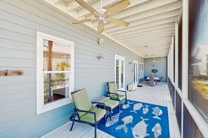 Eine überdachte Veranda mit zwei Stühlen, einer blauen Matte mit Fischmuster und einem Deckenventilator.