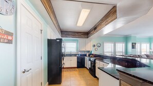 Una cucina con mobili bianchi, un frigorifero nero e un soffitto in legno.