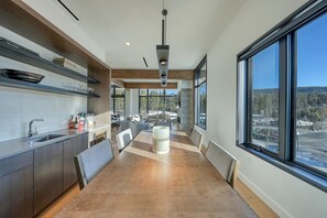 Une cuisine moderne dotée d’un îlot central, de grandes fenêtres et offrant une vue sur l’extérieur.