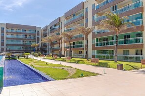 Un hotel moderno con piscina, palmeras y un patio bien cuidado.