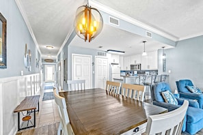 A spacious kitchen with white cabinets, a central island, and a dining area with a wooden table and chairs. - Fourth Floor Condo with Shared Pool, Ocean View, High-Speed WiFi, & Washer/Dryer (Mexico Beach)