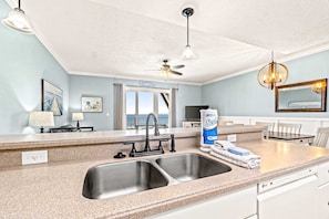 A kitchen with a double sink, a ceiling fan, and a view of the ocean. - Fourth Floor Condo with Shared Pool, Ocean View, High-Speed WiFi, & Washer/Dryer (Mexico Beach)