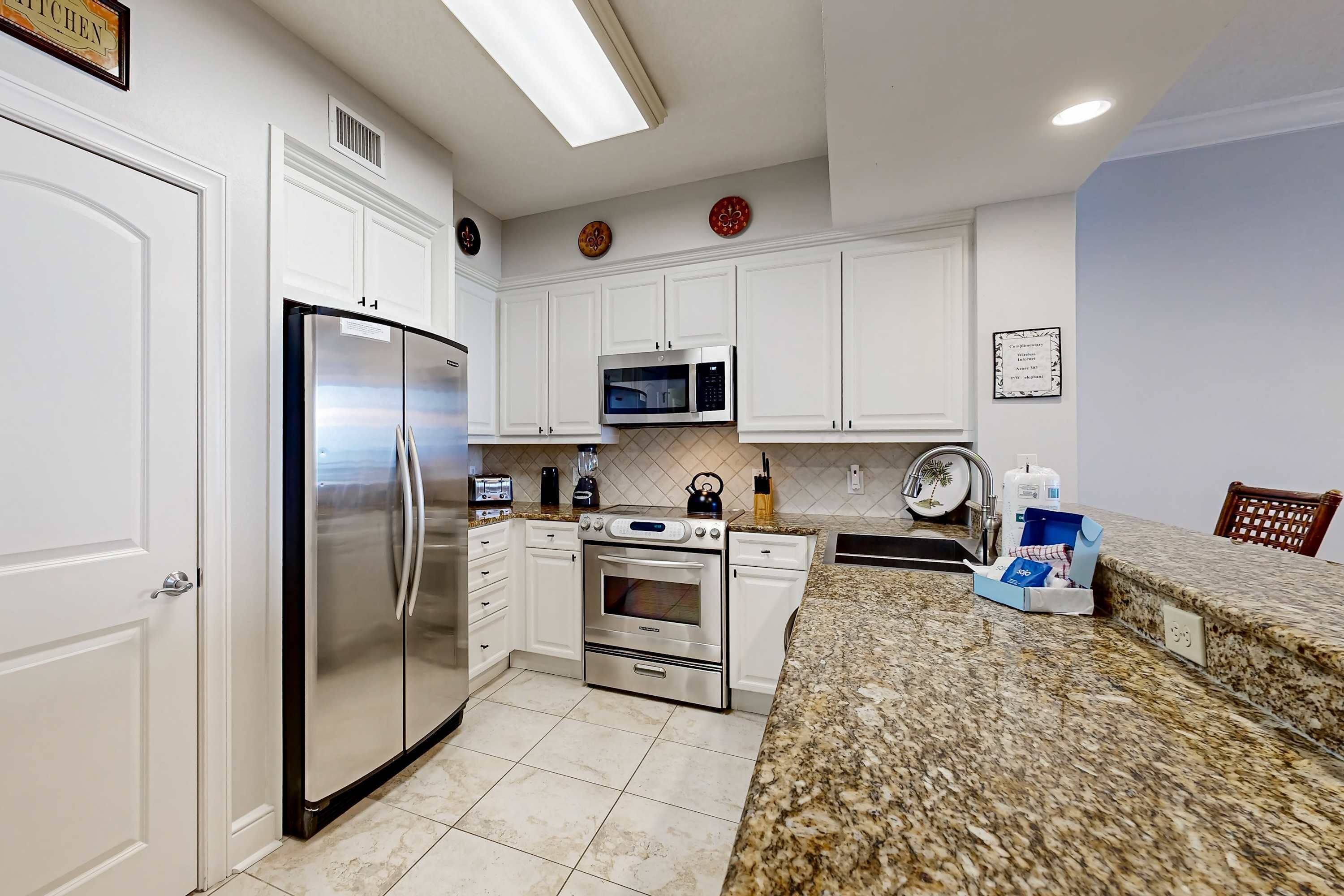 A modern kitchen with white cabinets, stainless steel appliances, and a granite countertop.