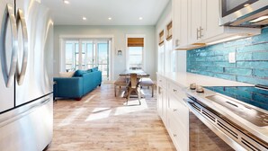 A modern kitchen with white cabinets, a blue tiled backsplash, and a stainless steel refrigerator. - Dog-friendly oceanfront home with a hot tub, washer&dryer & central AC (Cape San Blas)