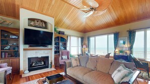 A cozy living room with a fireplace, a large flat-screen TV, and a comfortable sofa. - Gorgeous beachfront home - washer/dryer, deck & central AC - community pool (St. George Island)