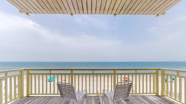 A wooden deck with two metal chairs facing a beach. - Gorgeous beachfront home - washer/dryer, deck & central AC - community pool (St. George Island)