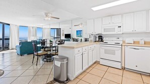 Cozinha moderna com armários brancos, uma ilha central e área de jantar com vista.