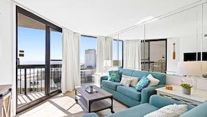 Uma sala de estar moderna com um sofá, mesa de centro e vista da cidade por grandes janelas.