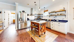 A spacious kitchen with a central island, stainless steel appliances, and wooden accents. - Snowbird-friendly home in gated community with hot tub, pool, balcony, & grill (Destin)